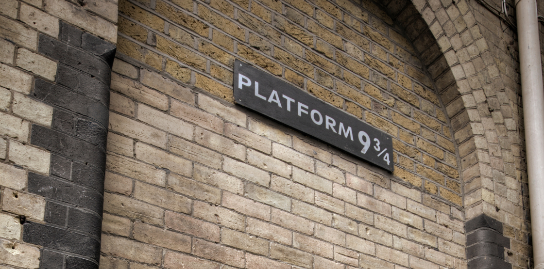 A brink wall at the train station displaying platform 9 3/4 in whit writing on a black slate.